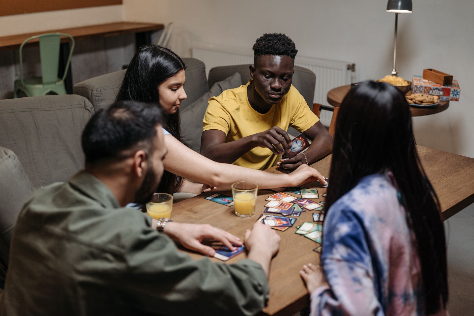 A group of friends around a table playing a card game with drinks